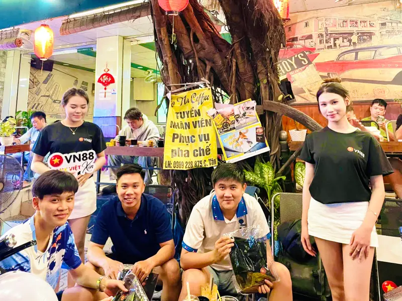 Nhóm anh em game thủ trẻ tuổi đang ngồi tại bàn uống nước và nhận các phần quà công nghệ là cục sạc dự phòng tiện lợi